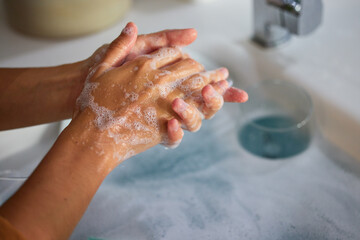 Fototapeta premium Hand wash, cleaning and sink washing for healthcare, wellness and virus safety in a bathroom. Skin health, bacteria cleaner and soap with hands using liquid disinfection for corona prevention