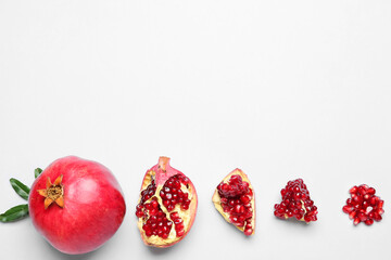 Whole pomegranates with pieces on white background