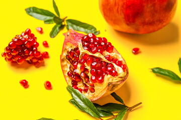 Piece of fresh pomegranate on yellow background, closeup