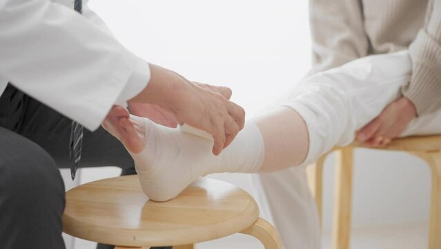 医者に包帯を巻かれる中年女性　医療イメージ