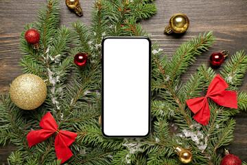 Composition with mobile phone, fir branches and Christmas decorations on wooden background, closeup