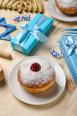 Plate with doughnut and gifts for Hanukkah celebration on wooden background, closeup