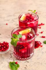 Glasses of cold pomegranate juice on color background