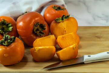 cook the persimmon with a knife. Sliced persimmon on a wooden table. Fresh ripe persimmons. Selective focus. 