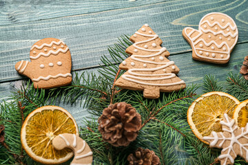 Composition with tasty Christmas cookies, fir branches and cones on color wooden background, closeup