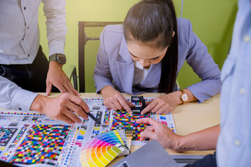 Crop image of worker checking print quality of media graphics proof print in printing industry....