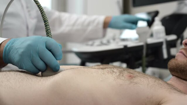 Ultrasound: A doctor checks a man's stomach with an ultrasound machine. Diagnosis of liver and pancreatic diseases. Examination of the body in the clinic office. Checking the status of sonograms