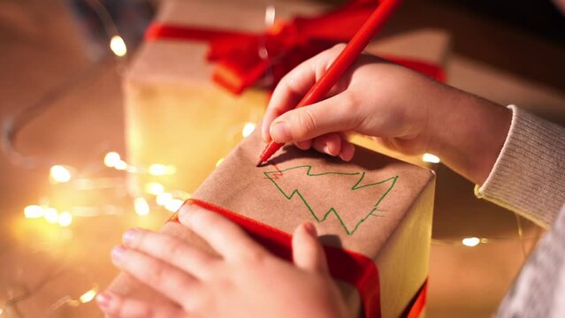 Family packing Christmas gifts in evening. Child and Grandfather hand wrapping the present box with craft paper and red ribbon. Happy time together.