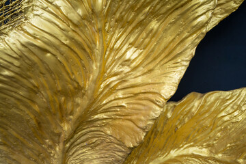 Gold leaf sculpture with line of vein with black background.