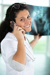 female doctor on the phone studying xray in clinic