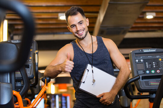 grinning athletic trainer with folded arms and confident expression