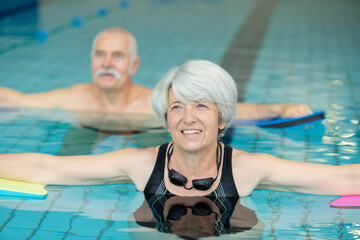 happy senior couple in aqua fitness class swimming pool