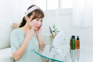 鏡を見て肌に悩む女性（ほうれい線・シワ）
