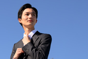 きゅっとネクタイを締めて未来に向かう若者のイメージ