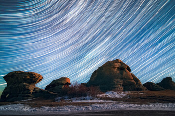 Star trails in the night sky above the ancient rock remains. Sanctuary on Big Allaki Lake.