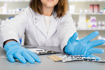 Closeup of female pharmacist in medical gloves selling new remedy pills