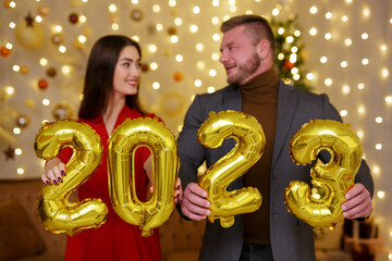 Male and female holding golden 2023 balloons in hands