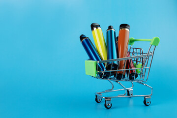 disposable vape in a trolley, electronic cigarettes in a shopping cart on a blue...