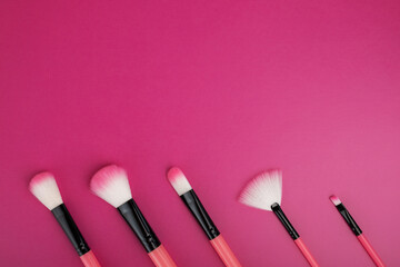 makeup brushes on a pink bright background with copy space