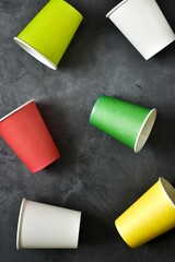 Set of colorful paper cups for coffee on a gray background. Top view. Vertical banner