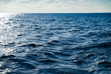 Bright blue Ocean water ripples background on a sunny day. Clean water consumption and natural resources