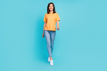 Full body photo of satisfied glad girl walking toothy smile isolated on blue color background
