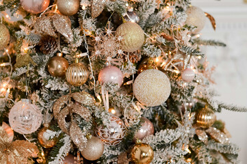 Close up of the luxury Christmas tree with white, silver and pink balls, snow and glowing garland.