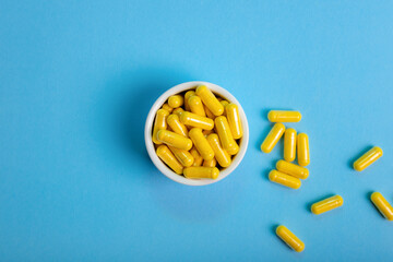 Yellow pills on light blue background top view.