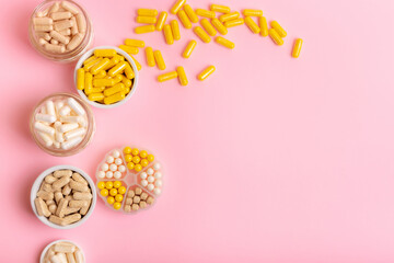 Food supplements, vitamins and minerals in forms of tablets, capsules and multivitamin meds from above on light pink background. Healthy lifestyle and good health thanks to preventative medicine.