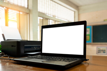 Fototapeta premium Open black laptop computer on a small chair table in classroom.Modern printer and laptop on table indoor.
