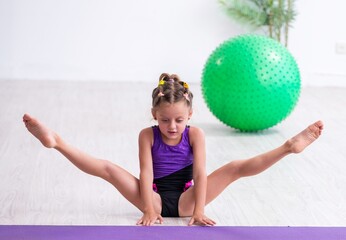 Little girl gymnast doing exercises indoors
