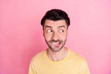 Photo of optimistic positive guy with brunet hairstyle yellow t-shirt bite lips look empty space...