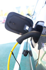 Detail of cable plugged into the electric car, charging the battery. Sustainability, electricity, load, renewable energy.