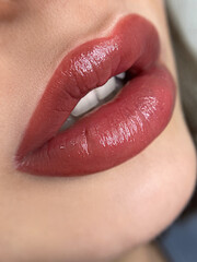 permanent makeup on the lips of a young woman of a delicate peach shade close-up, a girl after a cosmetic procedure with smooth and clean healthy skin. - obrazy, fototapety, plakaty