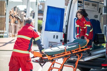 Paramedical workers taking a stretcher out of the EMS vehicle - obrazy, fototapety, plakaty