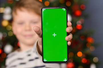 Child holding smartphone with green screen for modern technology on mockup template, watching...