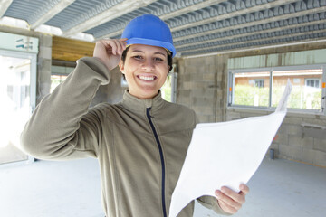 woman builder looking at architectural blueprint in new apartment