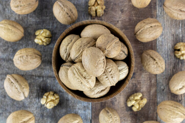 Walnut in a wooden bowl on a rustic background. Whole and halves of walnuts top view. Nuts in a wooden bowl.
