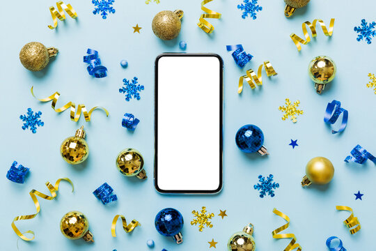 Christmas Online Shopping From Home Phone With Blank White Display Top View. Smart Mobile With Copy Space On Colored Background With Christmas Decorations Balls,. Winter Holidays Sales Background