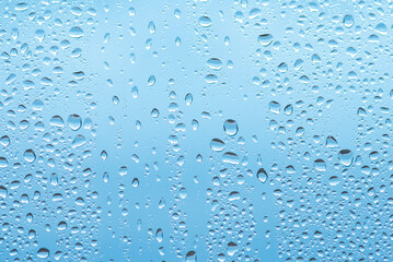Water drops on glass against blue sky