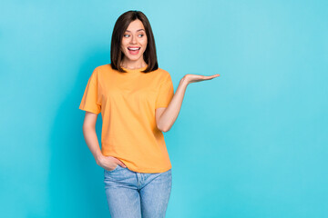Photo of pretty positive lady look hand palm hold demonstrate empty space isolated on blue color background