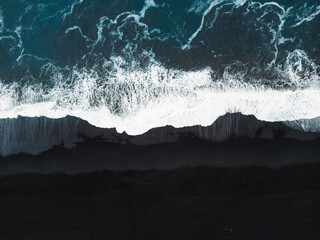 Directly above waves crashing on the black sand beach - Powered by Adobe