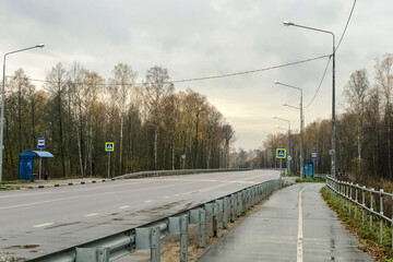 deserted highway with bus stops on both sides and pedestrian crossing road signs