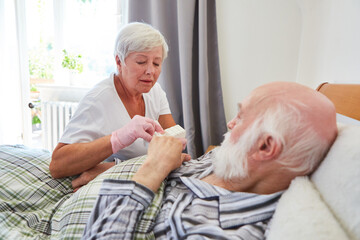 A geriatric nurse distributes pills to a sick senior citizen