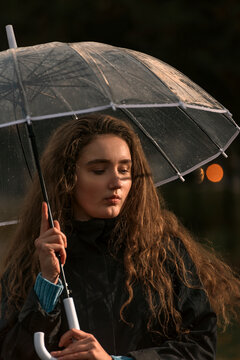 Sad Girl With Long Wavy Hair And Dimple In Chin Under Transparent Umbrella. Photo From Proximity Of Young Woman