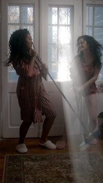 Two women dancing in the corridor holding brushes