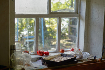 Old windowsill with tomatoes and pumpkin seeds. Dirty stained window in the village