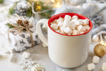Obraz na płótnie Canvas Christmas sweet drink concept. Christmas winter cozy cup hot chocolate drink with marshmallow and gifts, christmas lights, sweater knitted on a gray stone background.