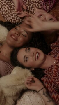 Three women lying on the floor dancing and playing with the balloons 