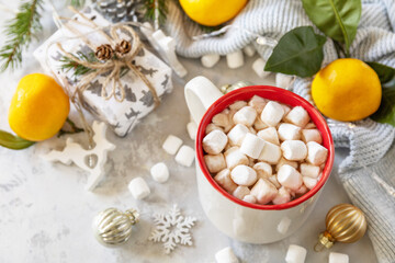 Christmas winter cozy cup with hot chocolate drink with marshmallow and gifts, tangerines on a gray stone background. Christmas food and drink concept. Copy space.